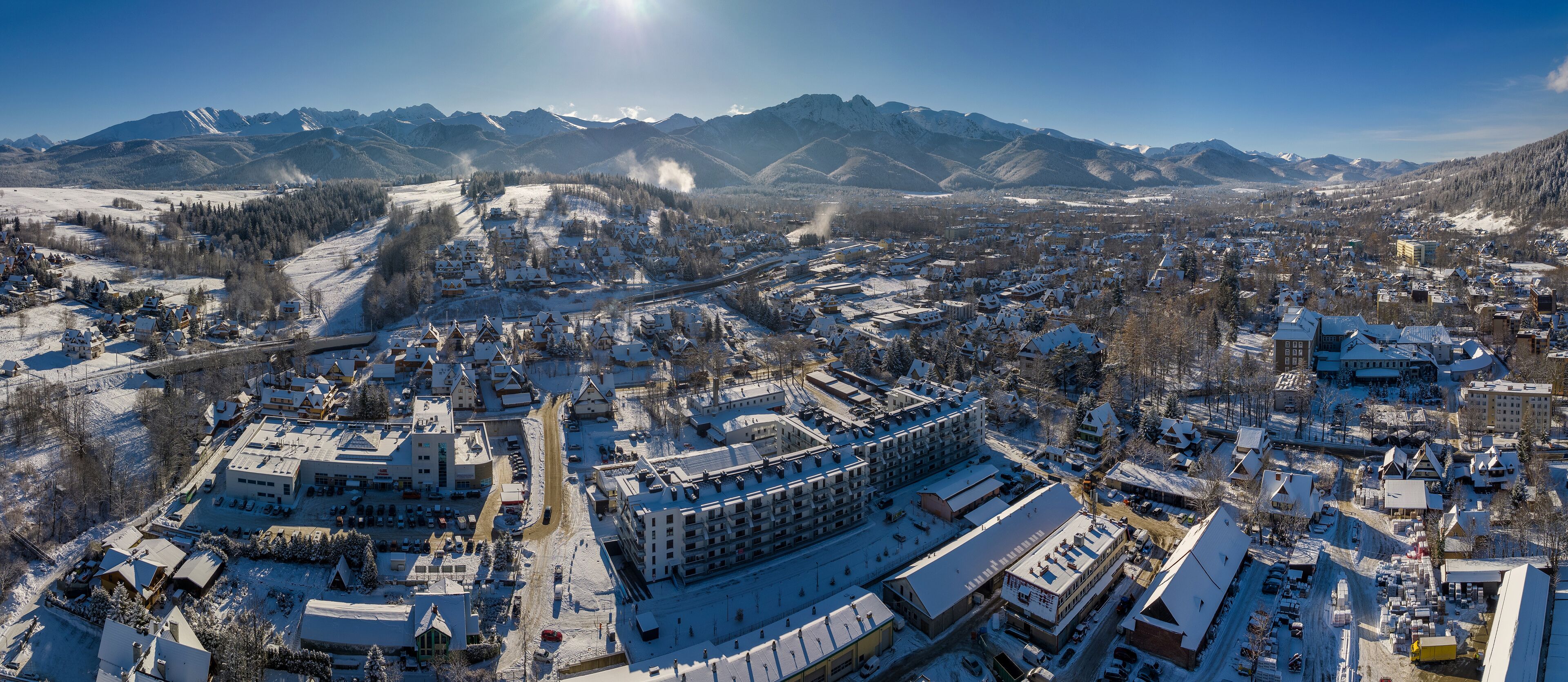 Una cittadina innevata con edifici residenziali e commerciali, circondata da montagne.
