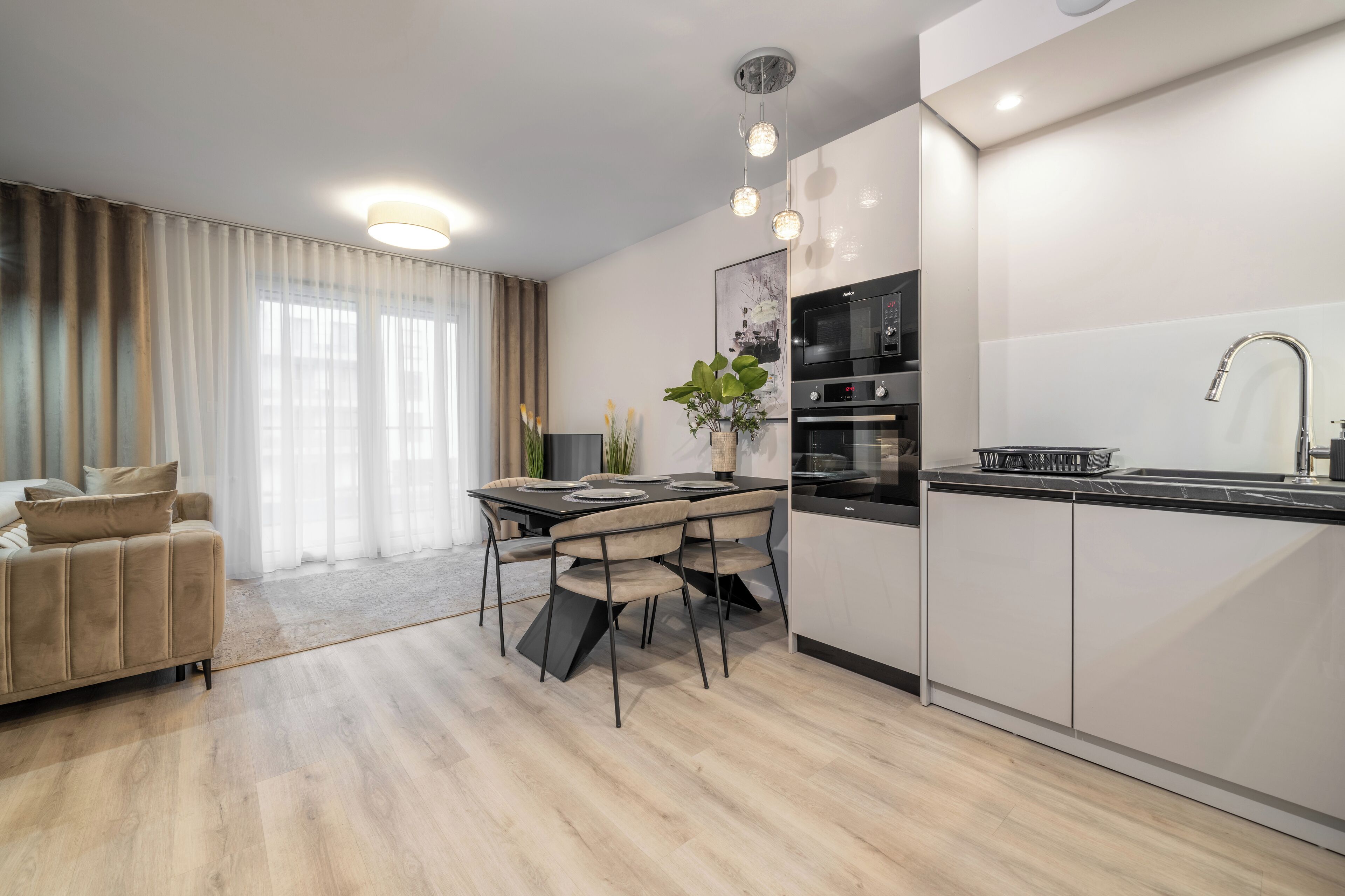 Eine moderne Küche mit Essbereich, einer Couch und einem großen Fenster mit Vorhängen.
