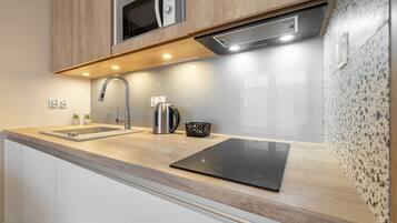 A modern kitchen with a stainless steel sink, a kettle, and a built-in stove.