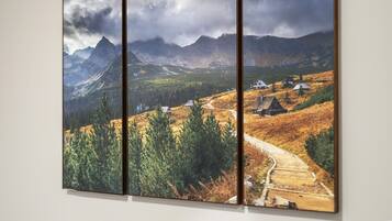 Pintura panorámica de un paisaje con montañas, un sendero y casas.
