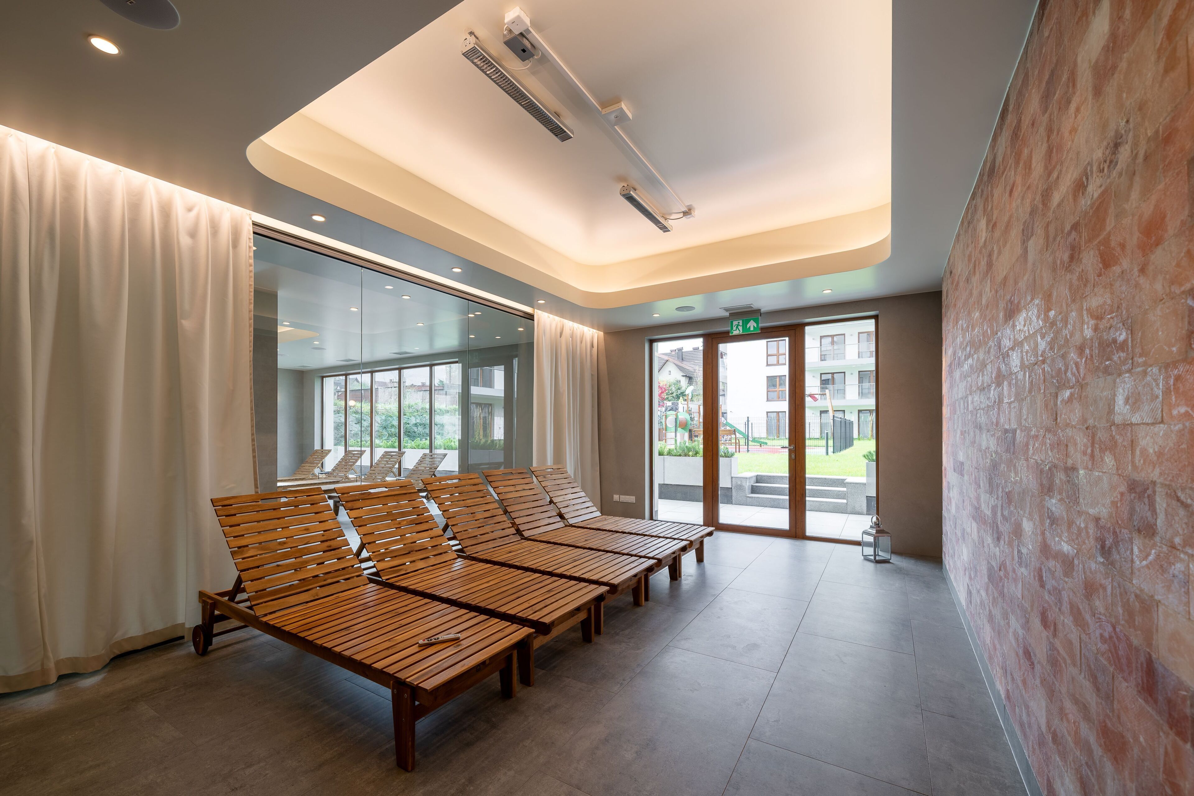 A modern waiting area with wooden benches, large windows, and a brick wall.