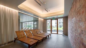 A modern waiting area with wooden benches, large windows, and a brick wall.