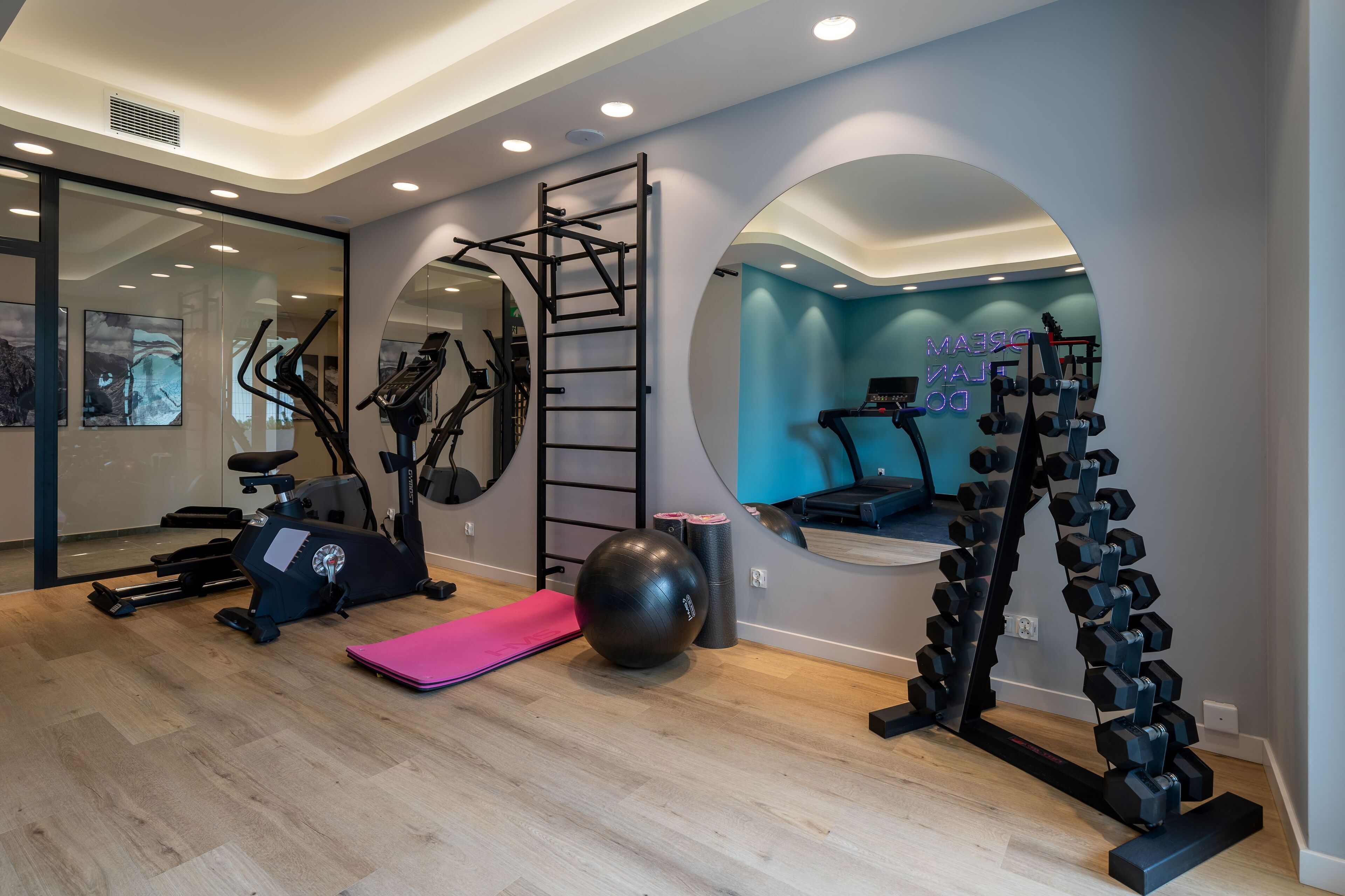 Een moderne sportschool met trainingsapparatuur, een grote spiegel en een neonbord.