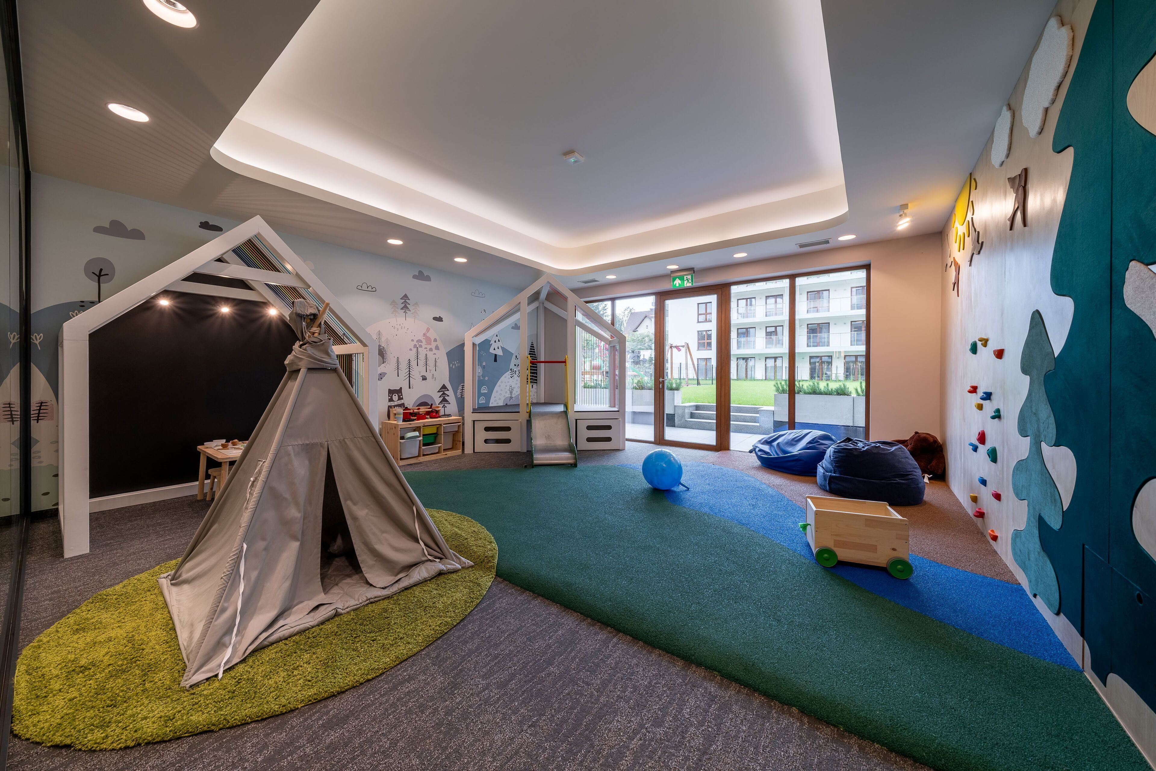 Un espace de jeux pour enfants avec une tente, un mur d’escalade et des tapis de jeu souples.