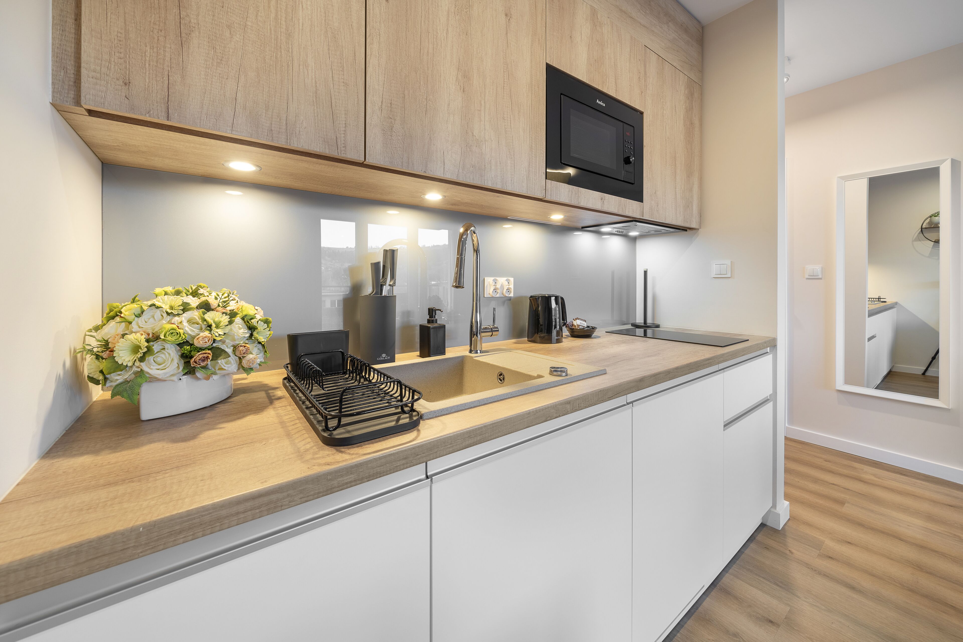 A modern kitchen with wooden cabinets, a stainless steel sink, and a microwave.