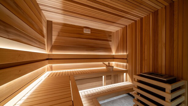 Uma sauna com bancos de madeira e um banco com uma pequena mesa.