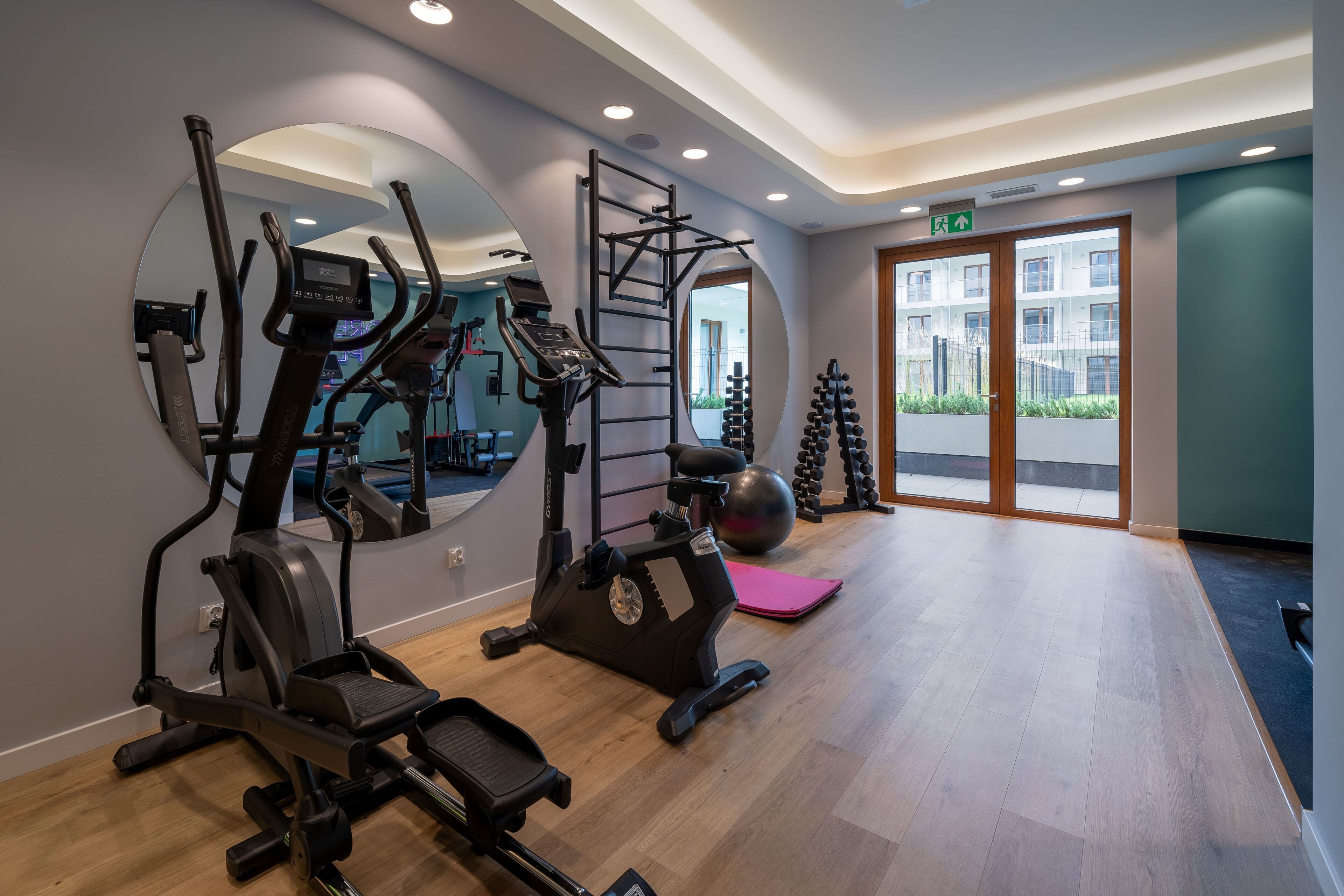 A gym with cardio machines, a pull-up bar, and exercise balls.