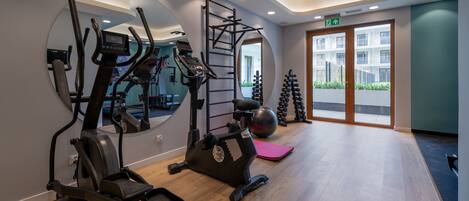 A gym with cardio machines, a pull-up bar, and exercise balls.