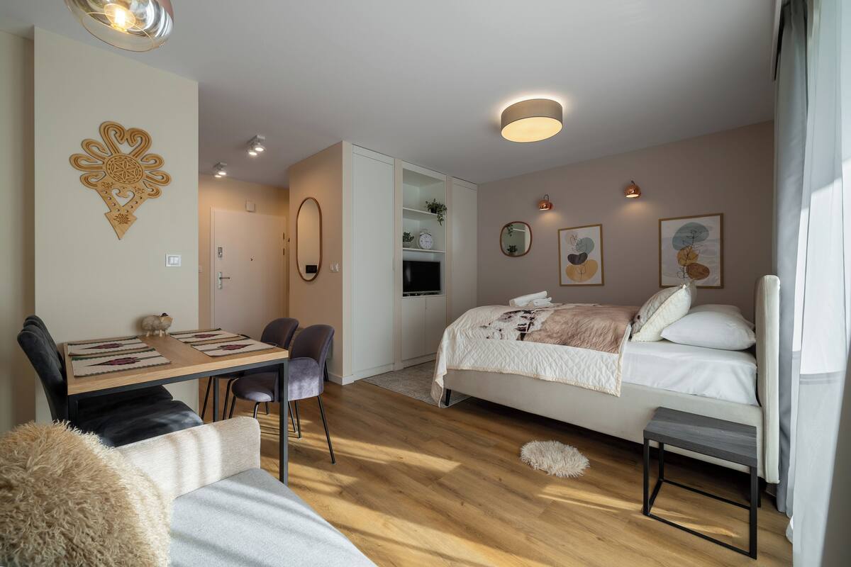 Un dormitorio con cama, mesita de noche y escritorio con sillas.