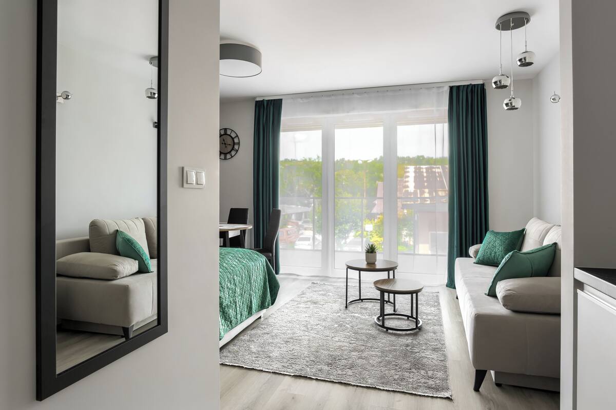 Una sala de estar moderna con un sofá, una mesa de centro y vistas a través de amplias puertas de cristal.