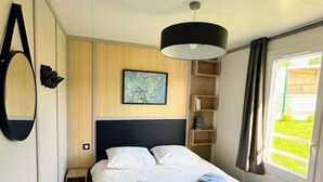 Une chambre d’hôtel avec un lit, une table de chevet, une lampe, un tableau au mur et une fenêtre avec des rideaux.