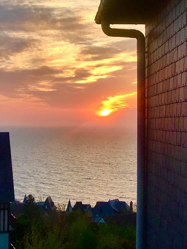 A sunset over a body of water with a view of houses in the foreground.
