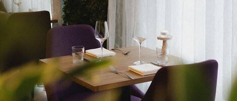A dining table set with wine glasses, a candle, and a glass of water.
