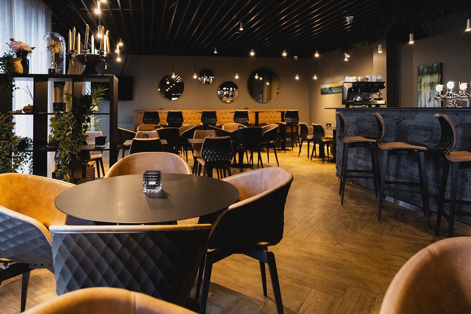 Ein modernes Café mit runden Tischen, Barhocker und einer Kaffeebar.