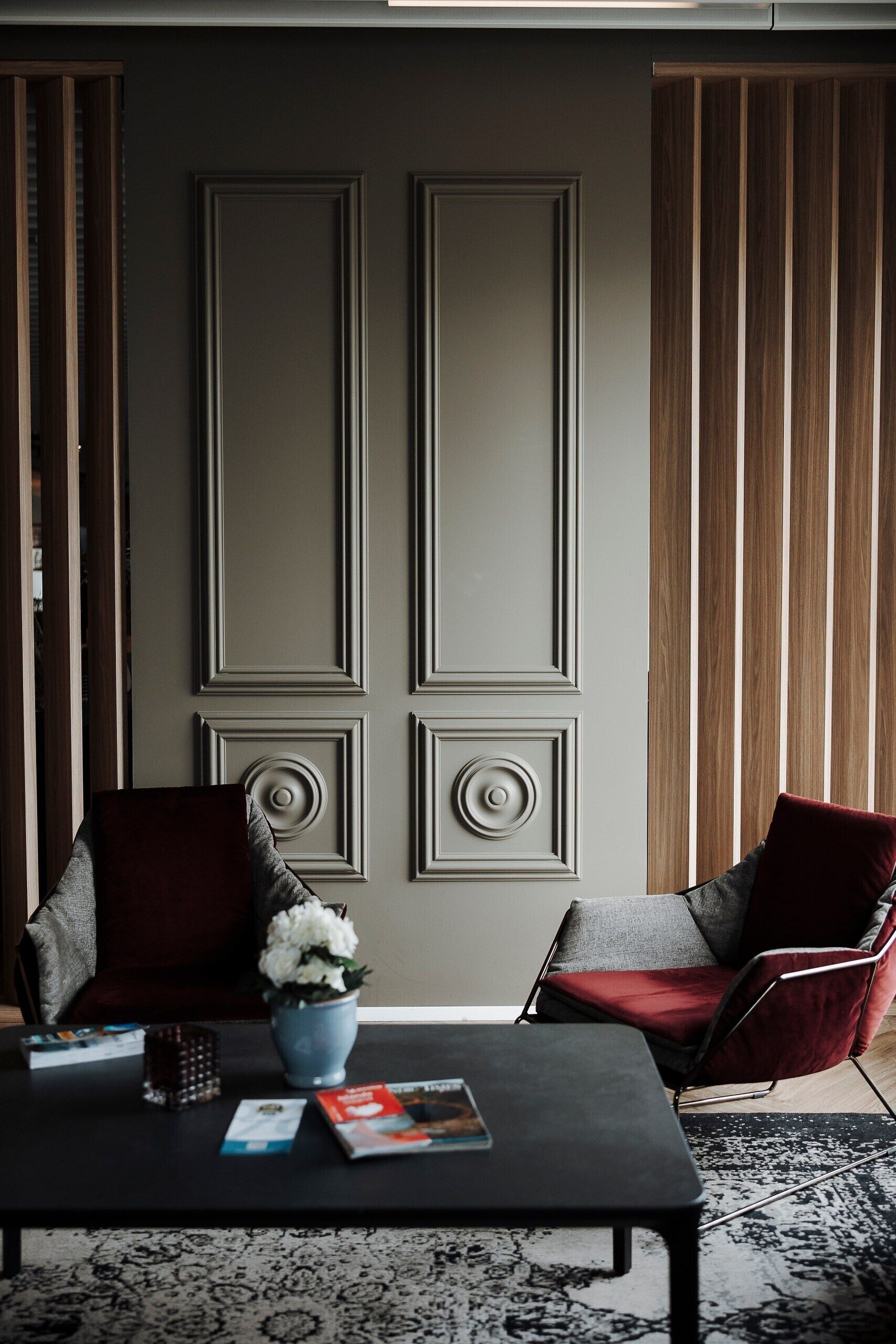 A modern room with two armchairs, a coffee table, and a decorative wall panel.