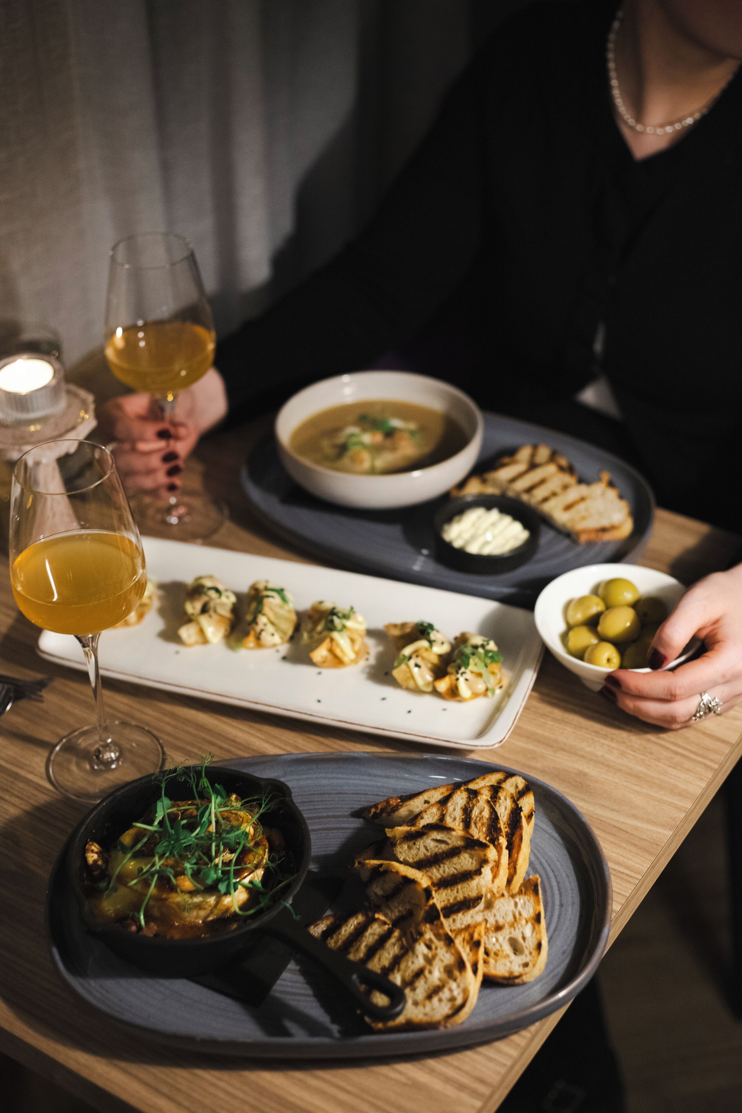 A dining table with various dishes, including a bowl of soup, a plate of bread, and a glass of wine.