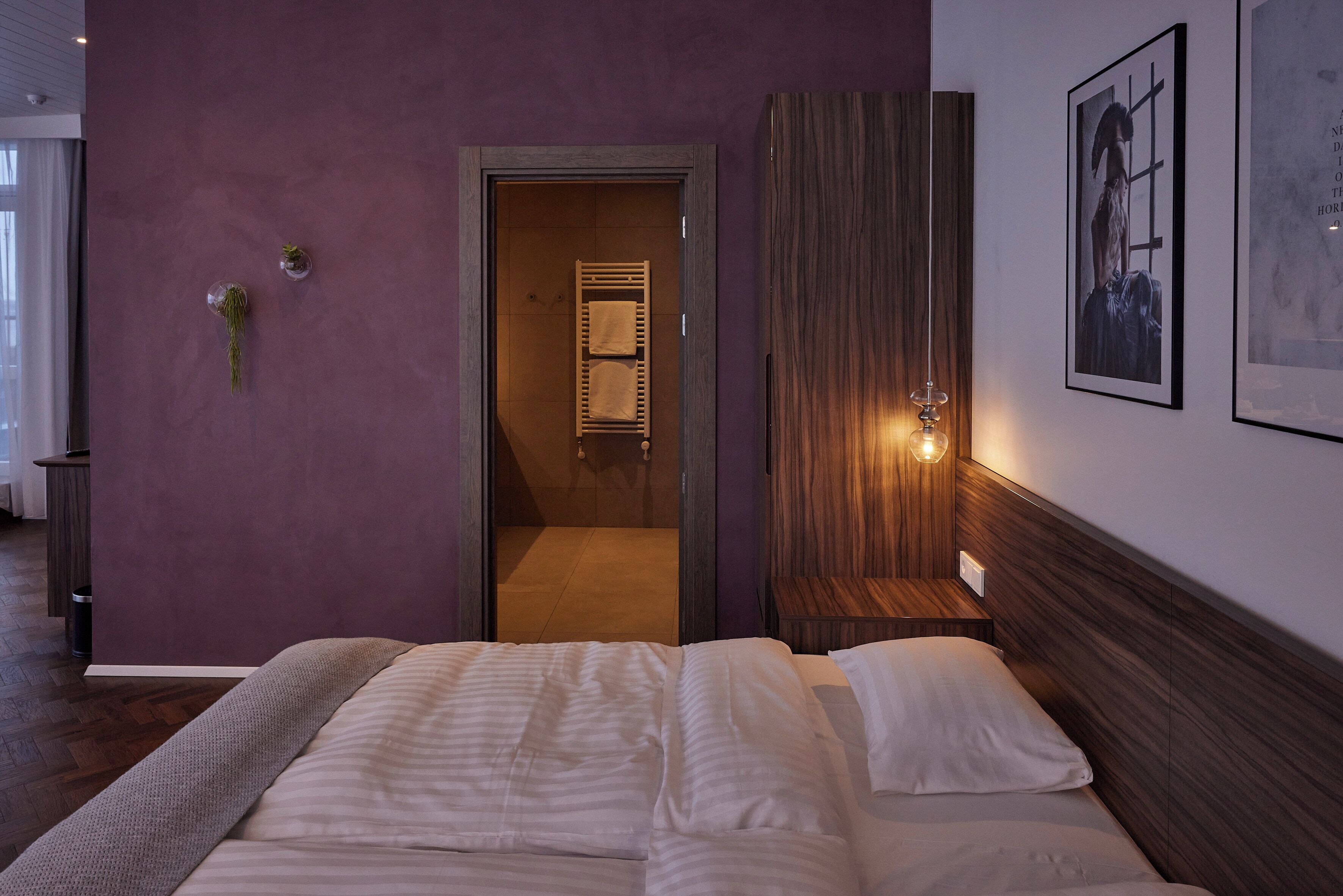 A bedroom with a large bed, a wooden headboard, and a wall-mounted light fixture.
