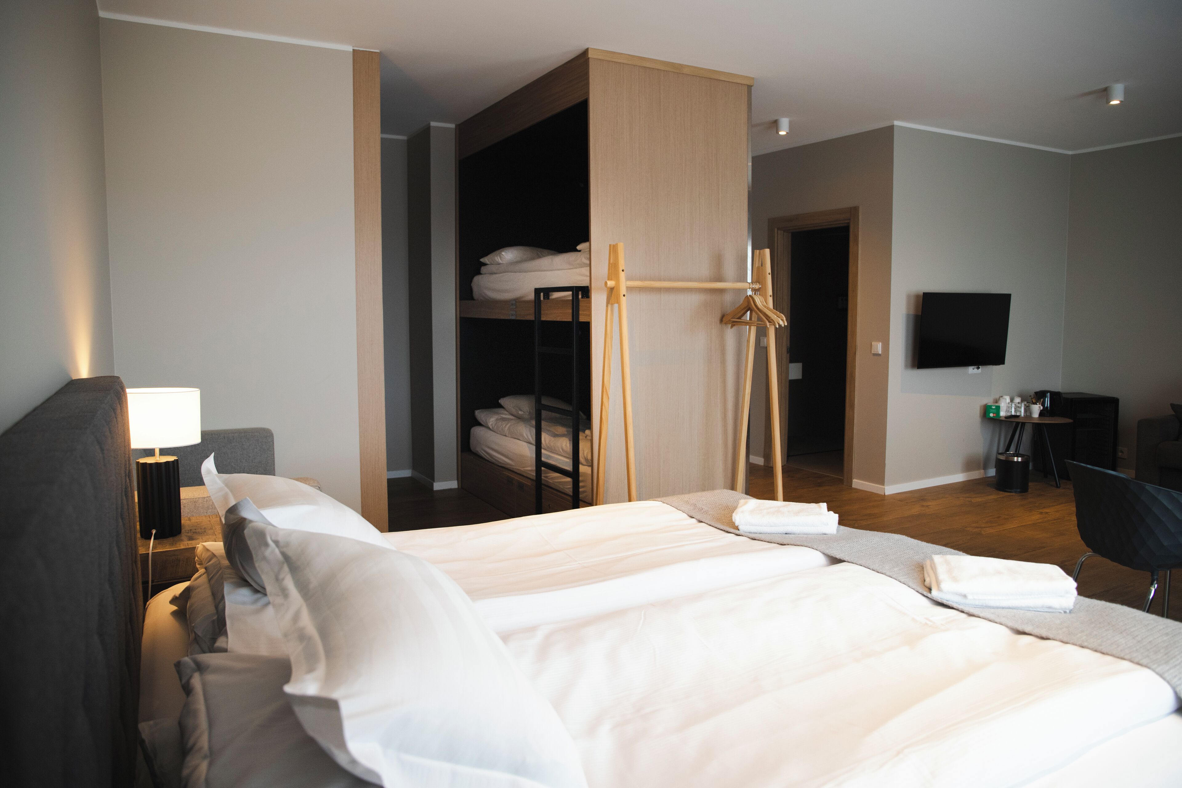Una habitación de hotel con una cama grande, un escritorio con silla, televisión y armario.