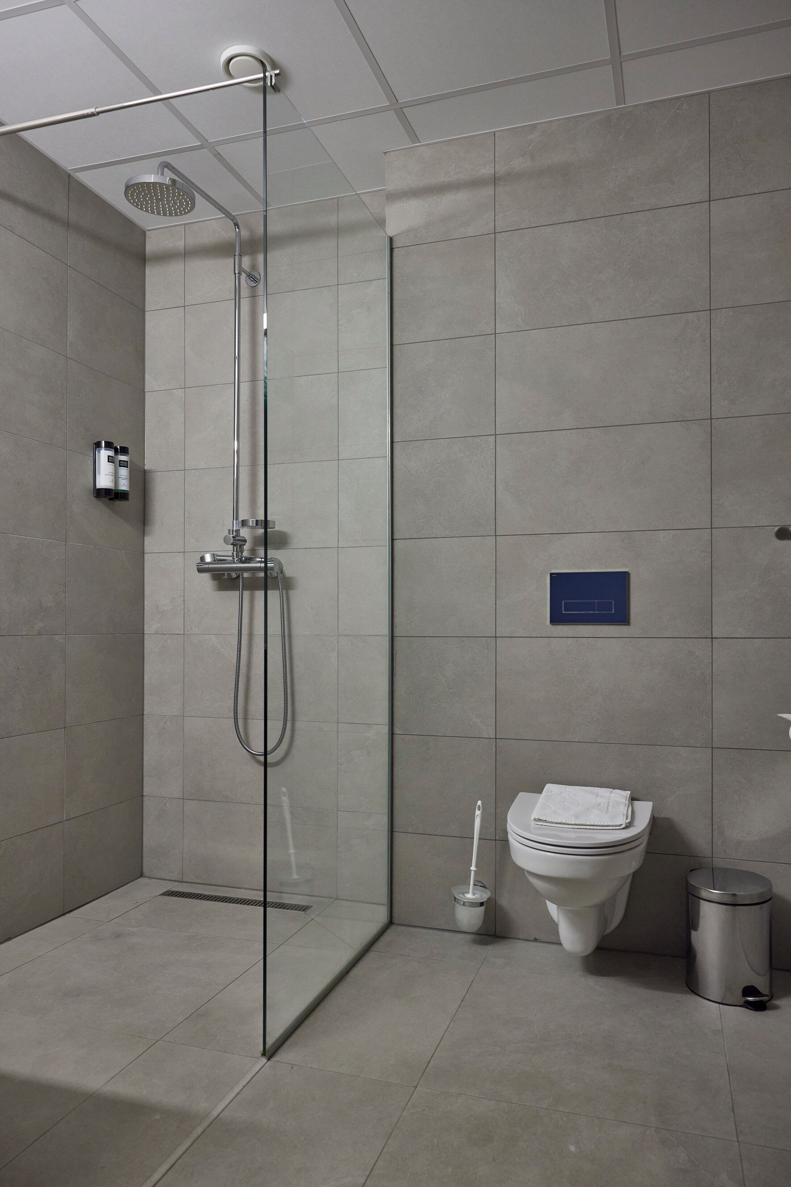 Un baño moderno con ducha de vidrio, inodoro y un cubo de basura.