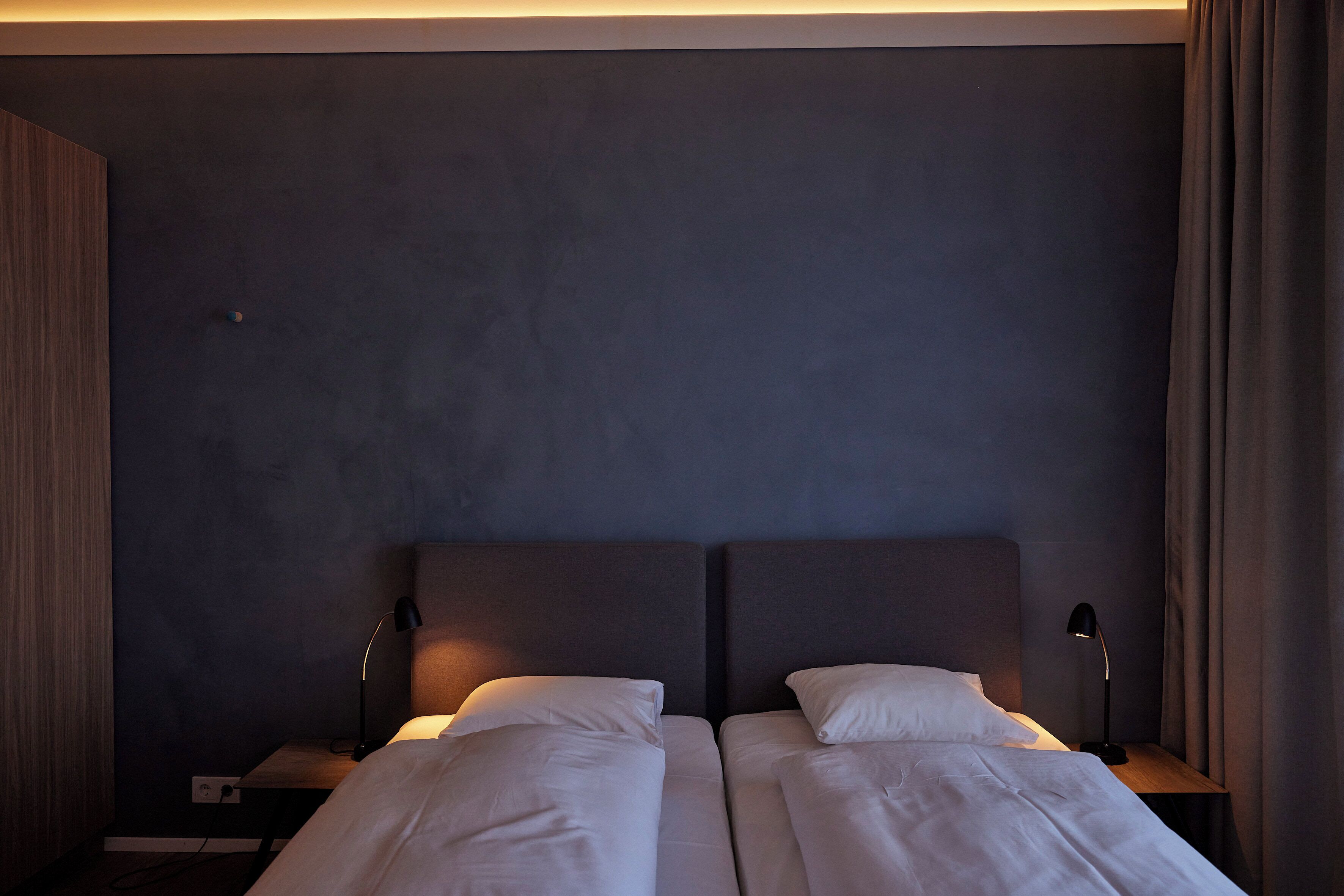 Una habitación de hotel con dos camas, una mesita de noche y una lámpara.