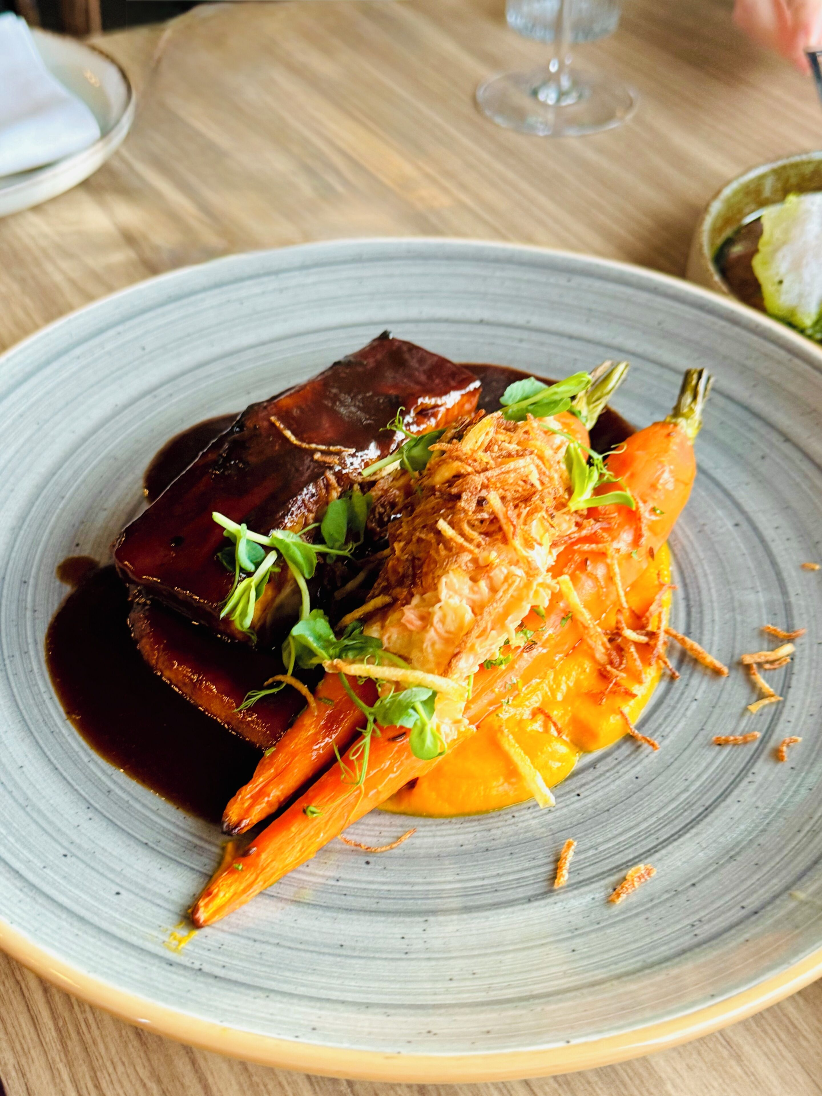A plate of food with a dark sauce, vegetables, and a garnish.