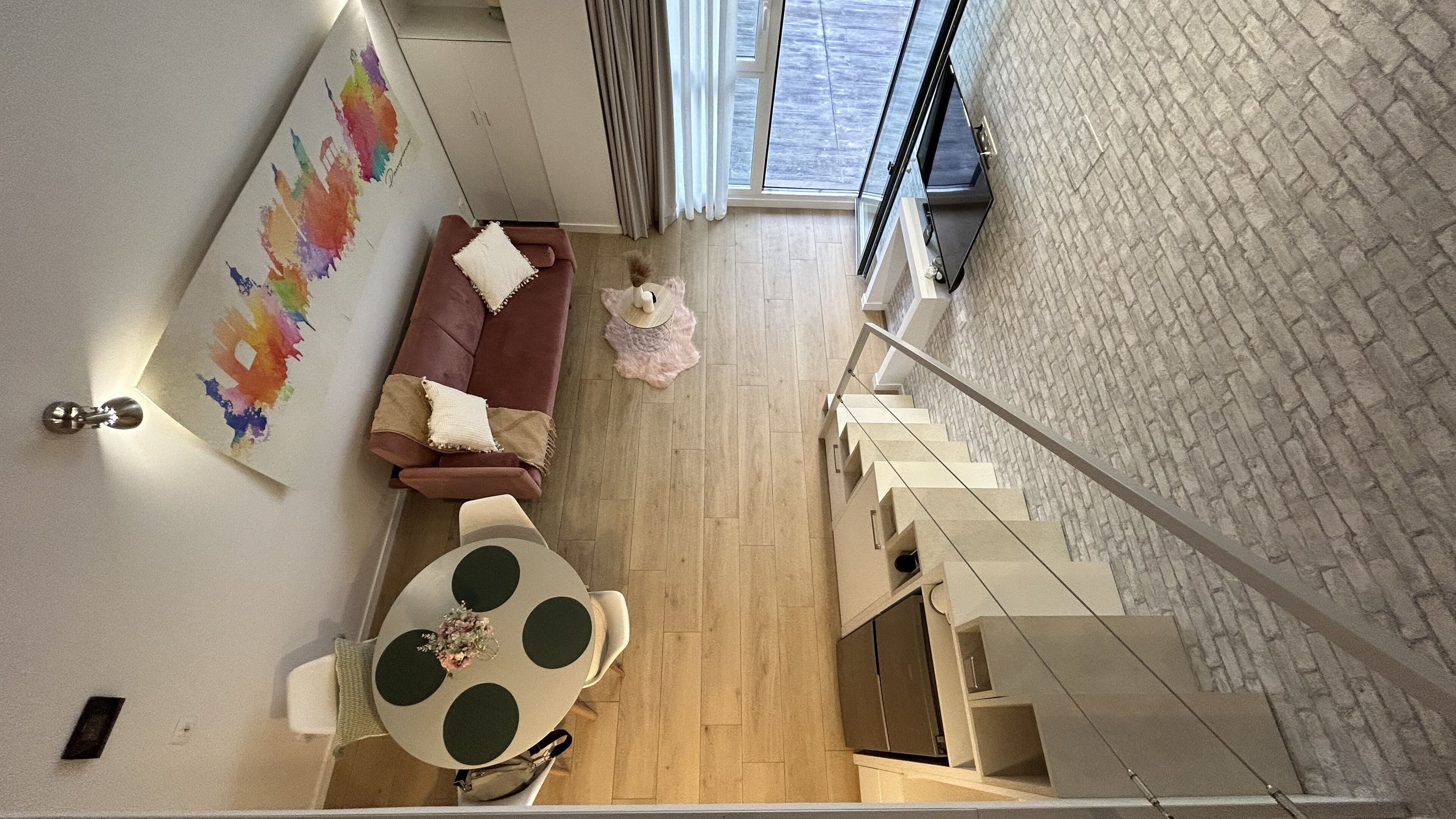 Een moderne woonkamer met een bruine bank, een ronde tafel en een trap naar een hoger niveau.