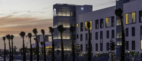 A modern hotel with a prominent tower, multiple windows, and a well-lit facade.