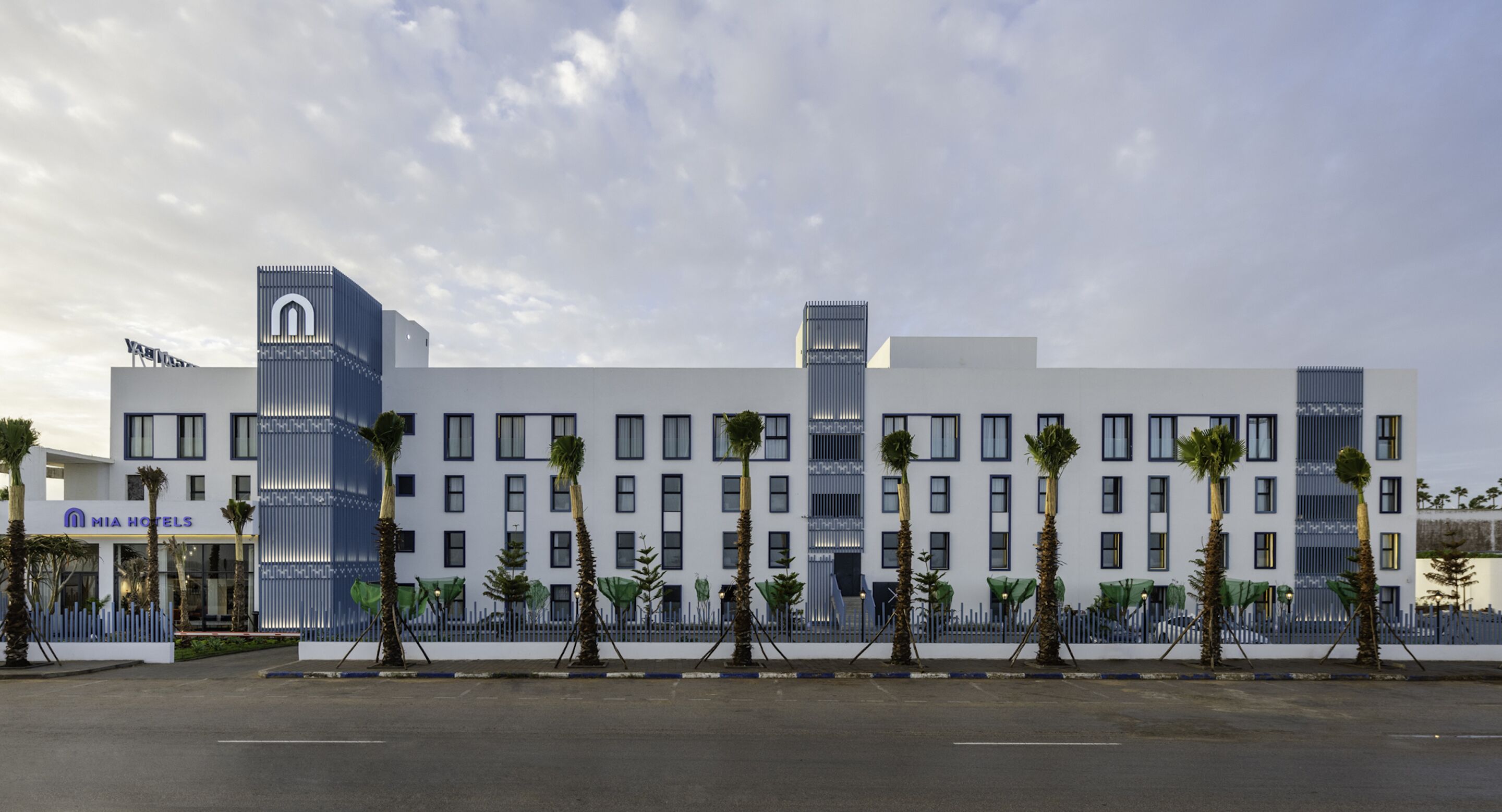 A modern hotel with a white facade, multiple floors, and a prominent 'MIA' sign.