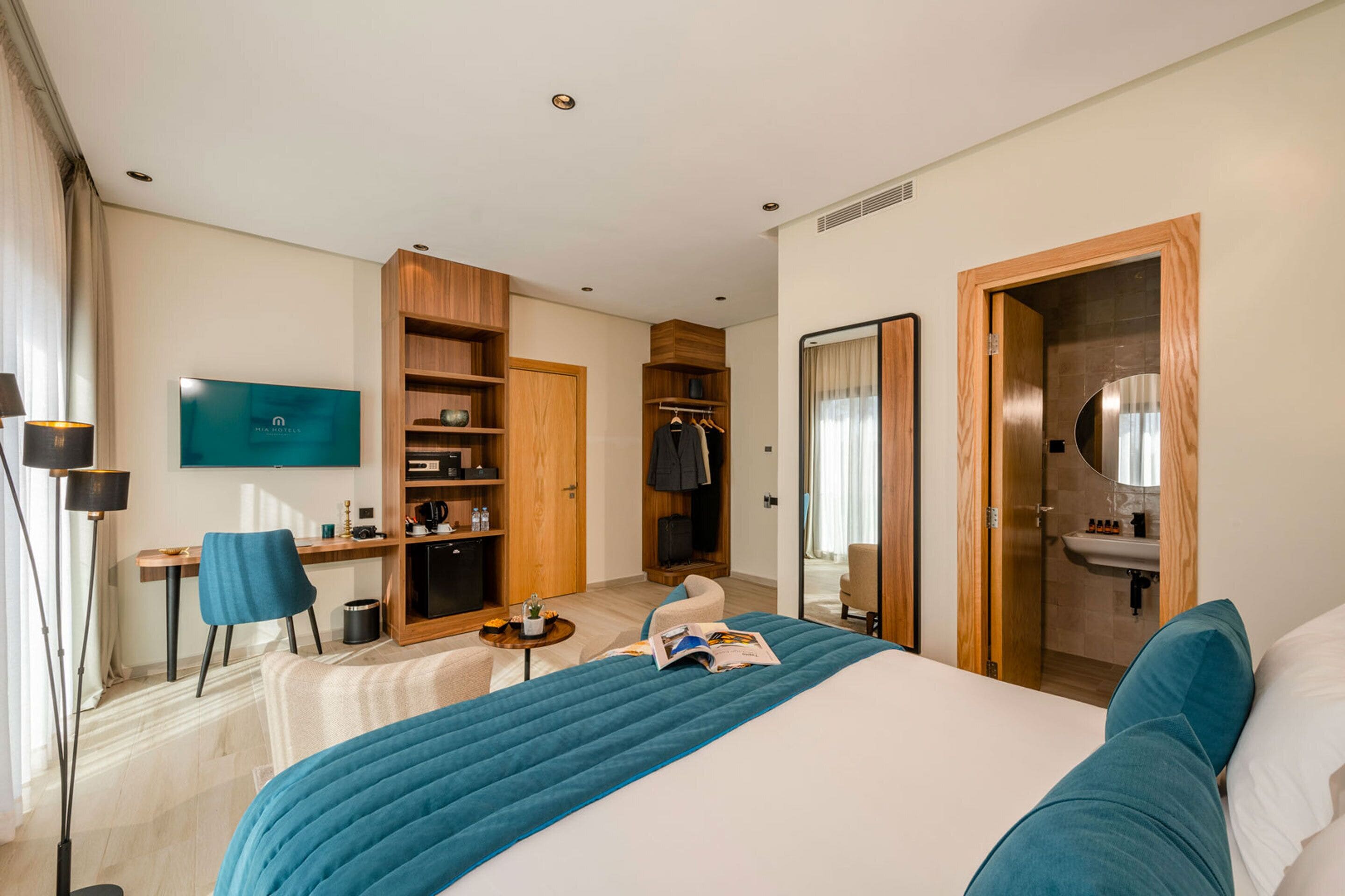A hotel room with a bed, a desk, a chair, a TV, a wardrobe, and a bathroom.