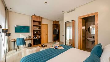 A hotel room with a bed, a desk, a chair, a TV, a wardrobe, and a bathroom.