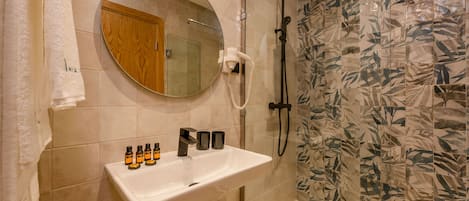 Un baño con lavamanos, espejo y ducha blancos.