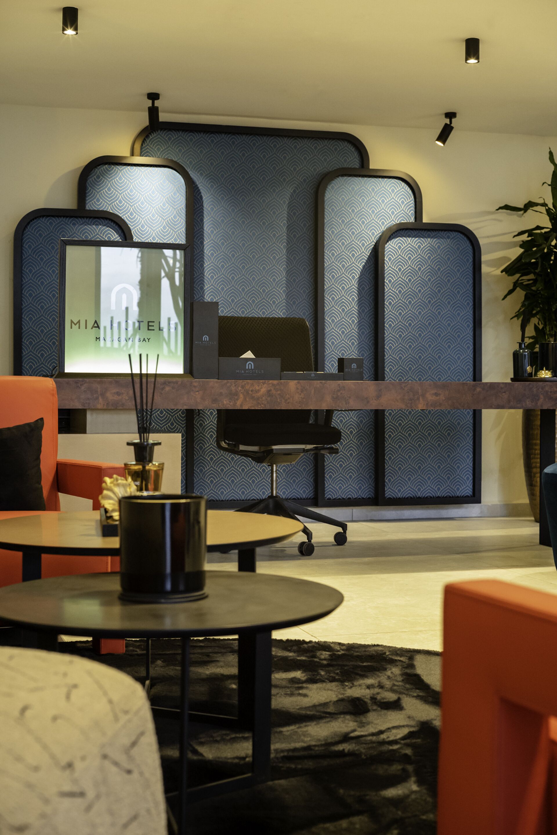 Un moderno vestíbulo de hotel con mostrador de recepción, zona de estar y elementos decorativos.