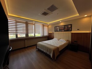 Camera d'albergo con un letto, finestre con persiane, una testiera, un'opera d'arte a parete e una bocchetta di ventilazione al soffitto.