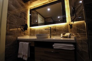 Un bagno con un lavabo in marmo, uno specchio grande e un portascopevoli.