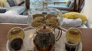 A dining table with a tea pot, a glass cloche, and four containers of cream. - Rooms At Babbacombe (Torquay)