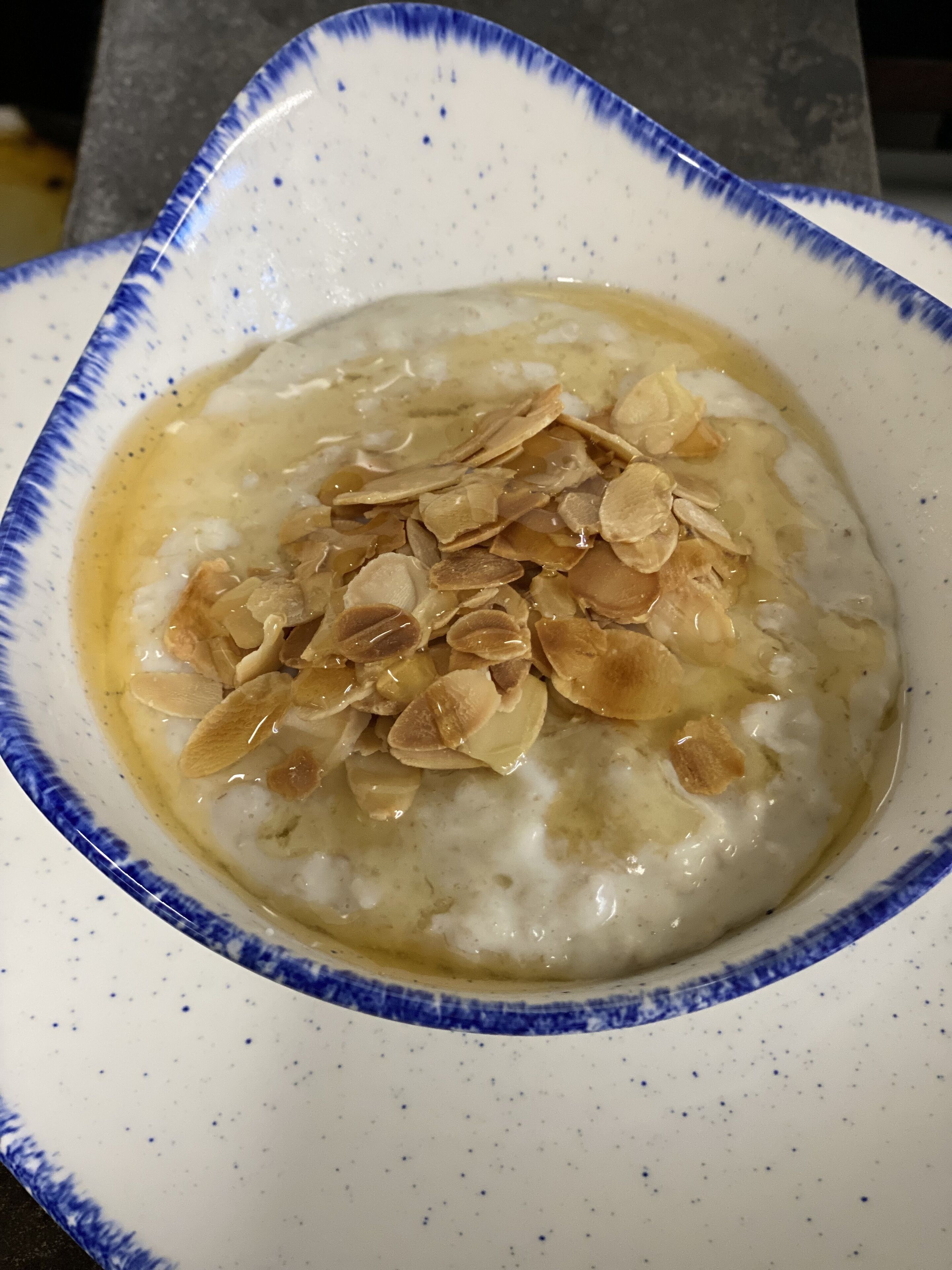 A bowl of oatmeal topped with sliced almonds.