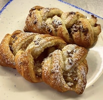 A plate of braided pastries dusted with powdered sugar.
