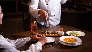 Un chef préparant un plat à une table dans un restaurant.