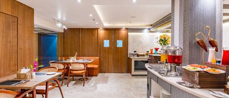 A modern hotel dining area with wooden furniture, a buffet counter, and a blue door in the background.