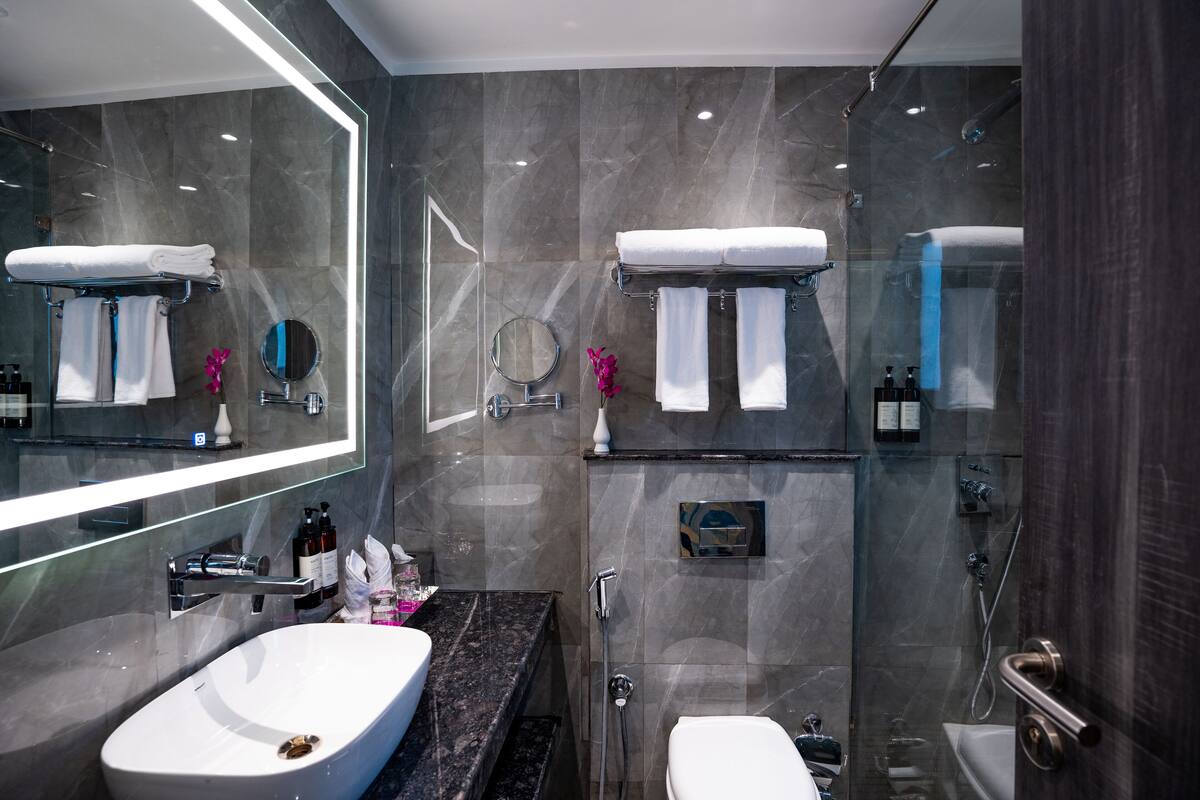 A modern bathroom with a large mirror, a sink, a toilet, and a shower area.