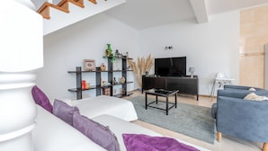 En moderne stue med sofa, sofabord, fjernsyn og bogreol.