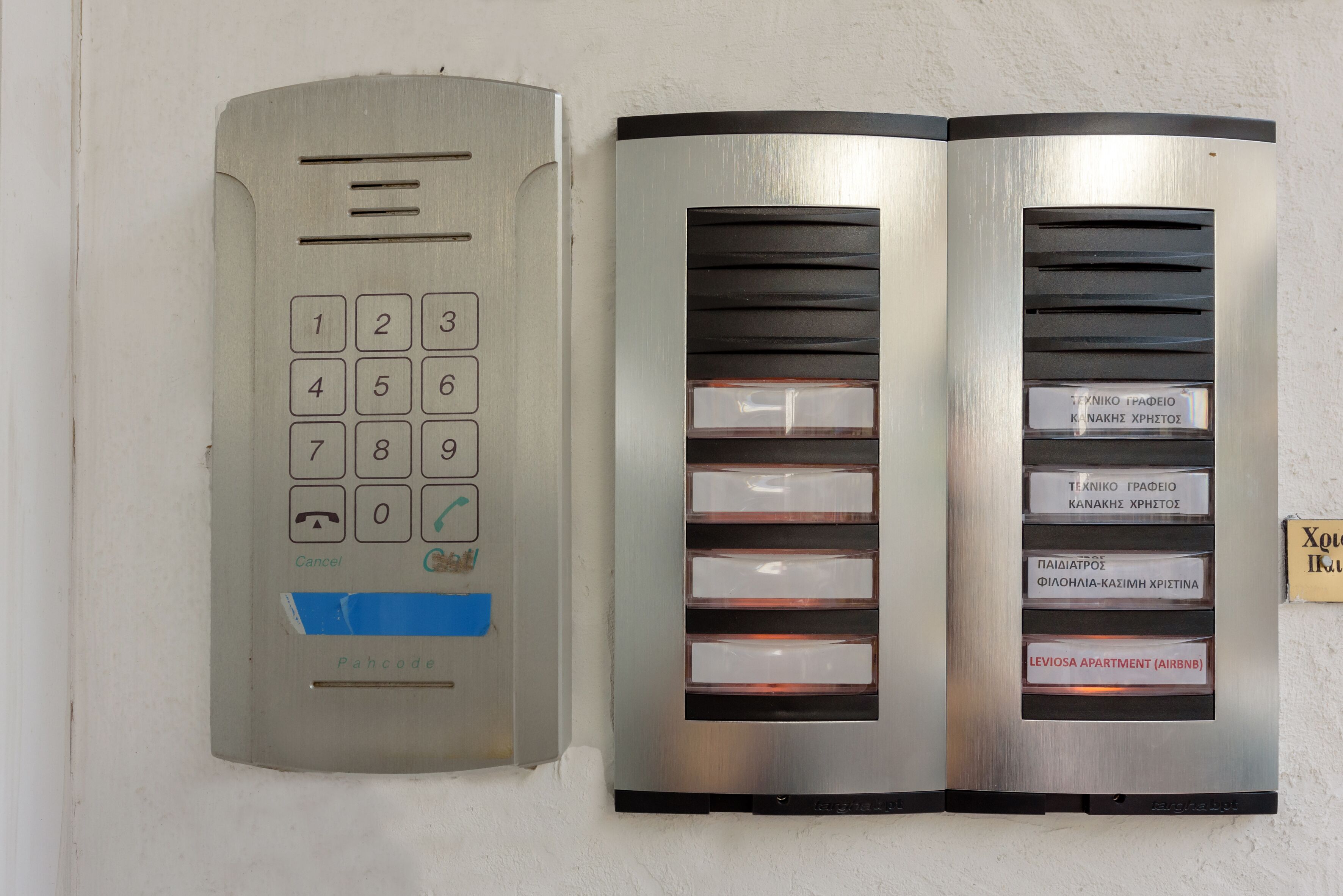 Ascensor empotrado en la pared con teclado numérico y panel de botones etiquetados para diferentes apartamentos.