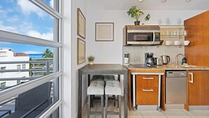 Una cocina moderna con microondas integrado, cafetera y lavavajillas. Hay una ventana con vistas a edificios y una planta en la encimera.