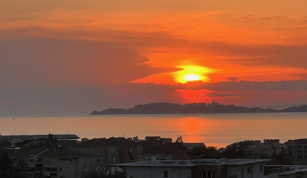 A sunset over a coastal city with buildings in the foreground.
