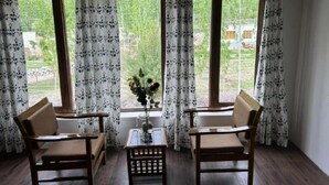 Une pièce comprenant deux chaises en bois, une petite table et un vase avec des fleurs.