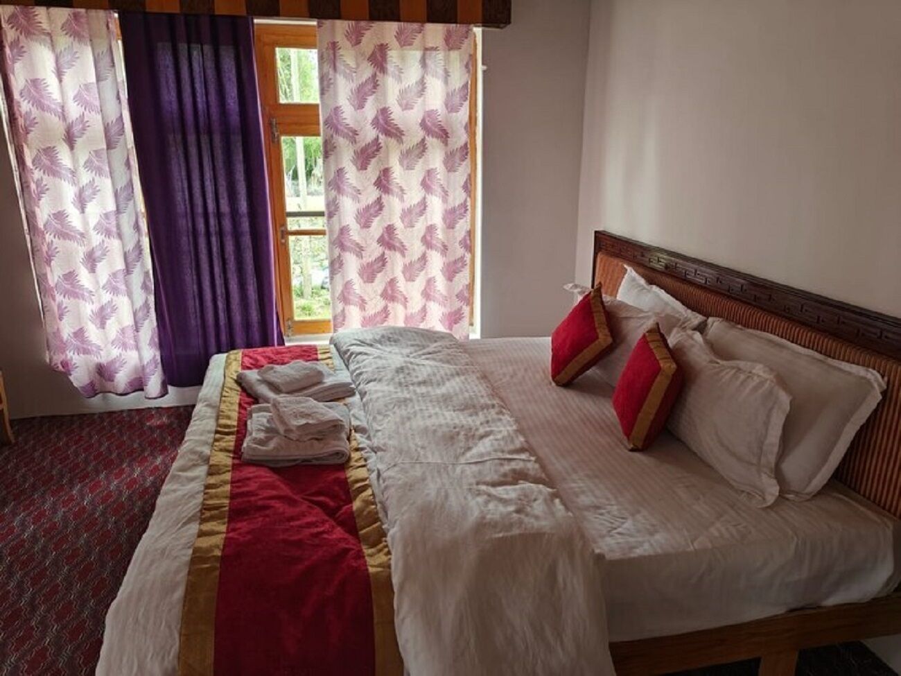 A neatly made bed with a red and white bedspread, a wooden headboard, and two red pillows.
