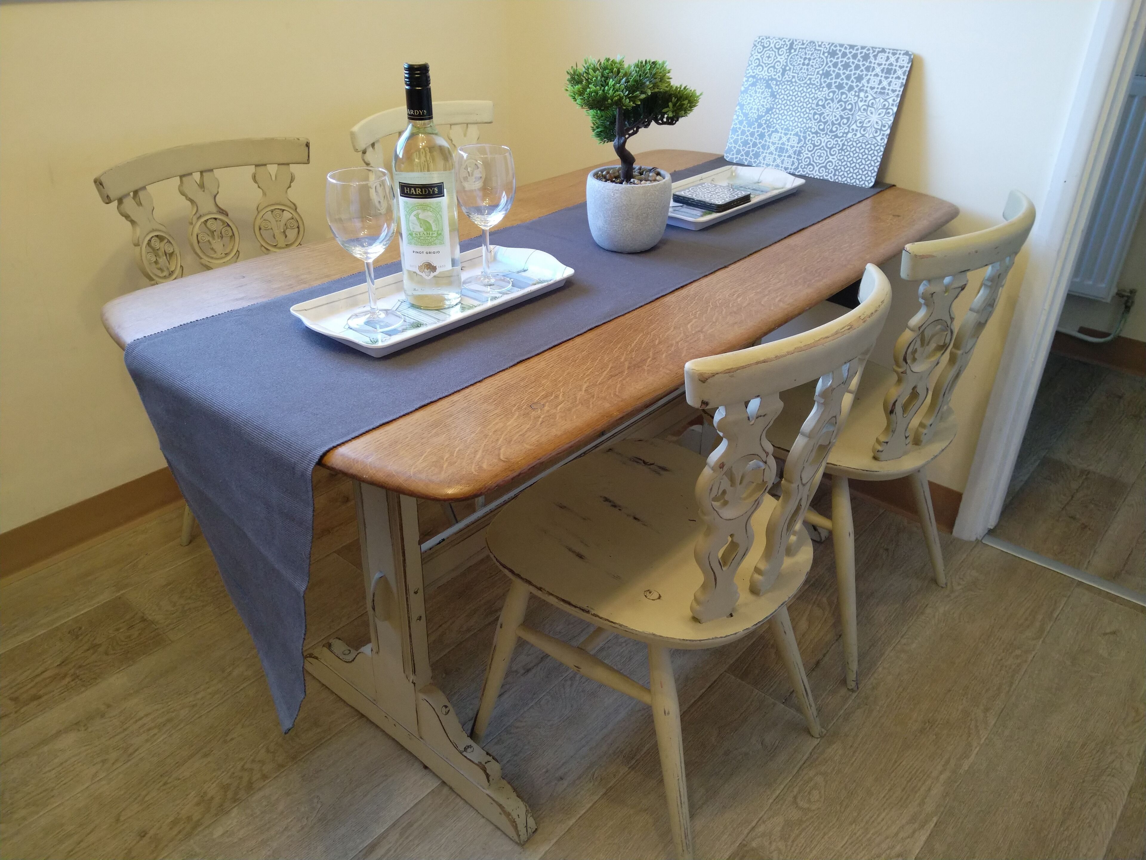 A dining table with a bottle of wine, two glasses, a small potted plant, and a decorative tray.