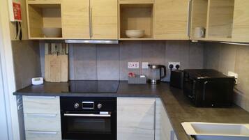 A modern kitchen with wooden cabinets, a built-in oven, a coffee maker, and a toaster.
