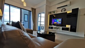 A modern living room with a leather sofa, a flat-screen TV, and a balcony with a view. - Thermospace Management (Malacca City)