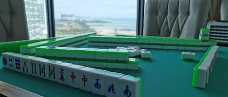 A mahjong table set up indoors with a view of a cityscape through large windows.